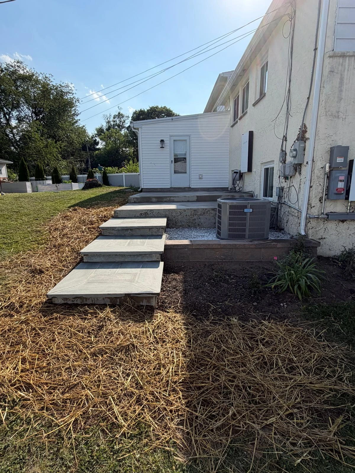 Exterior concrete steps beside a white house.