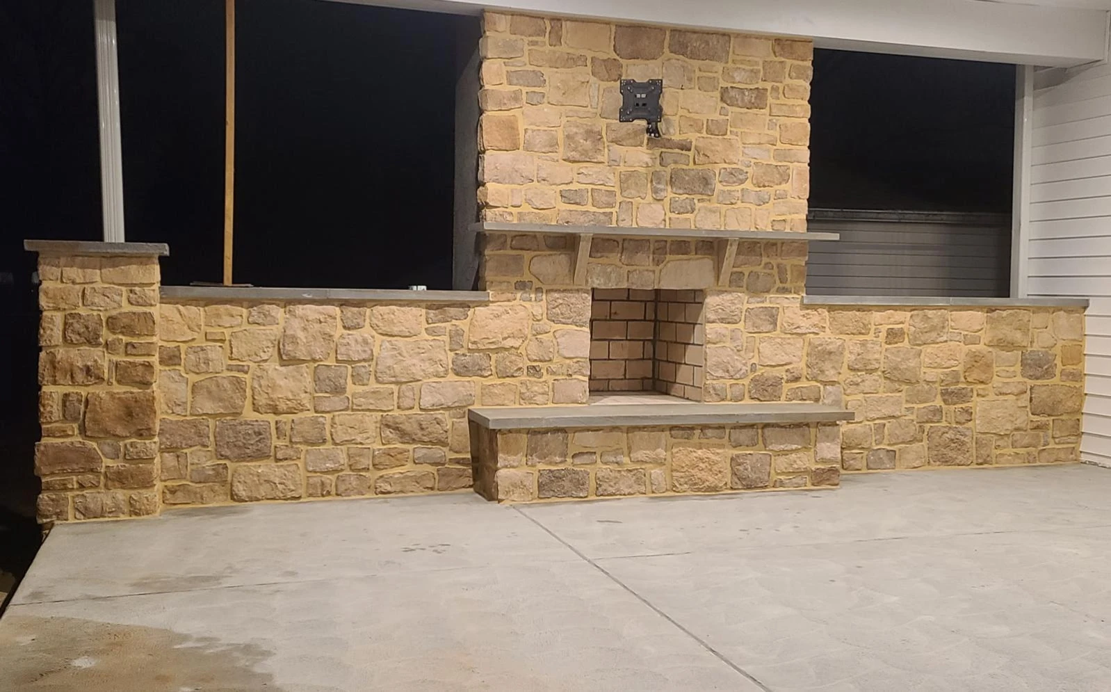 Stone fireplace and surrounding masonry in a covered space.